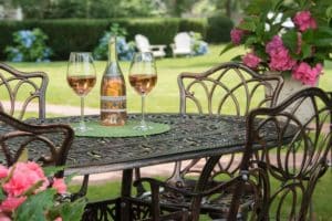 bottle of wine with glasses on outdoor iron table with flowers