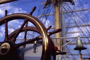 historic ship wheel and sail