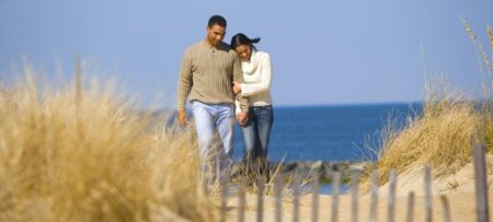 a couple walk hand in hand from the beach on a sunny day