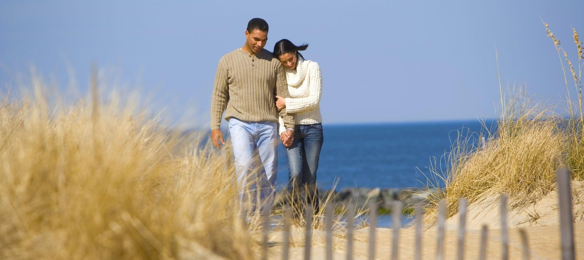 a couple walk hand in hand from the beach on a sunny day