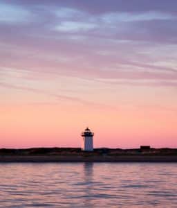 Lighthouse overlooking water at sunset