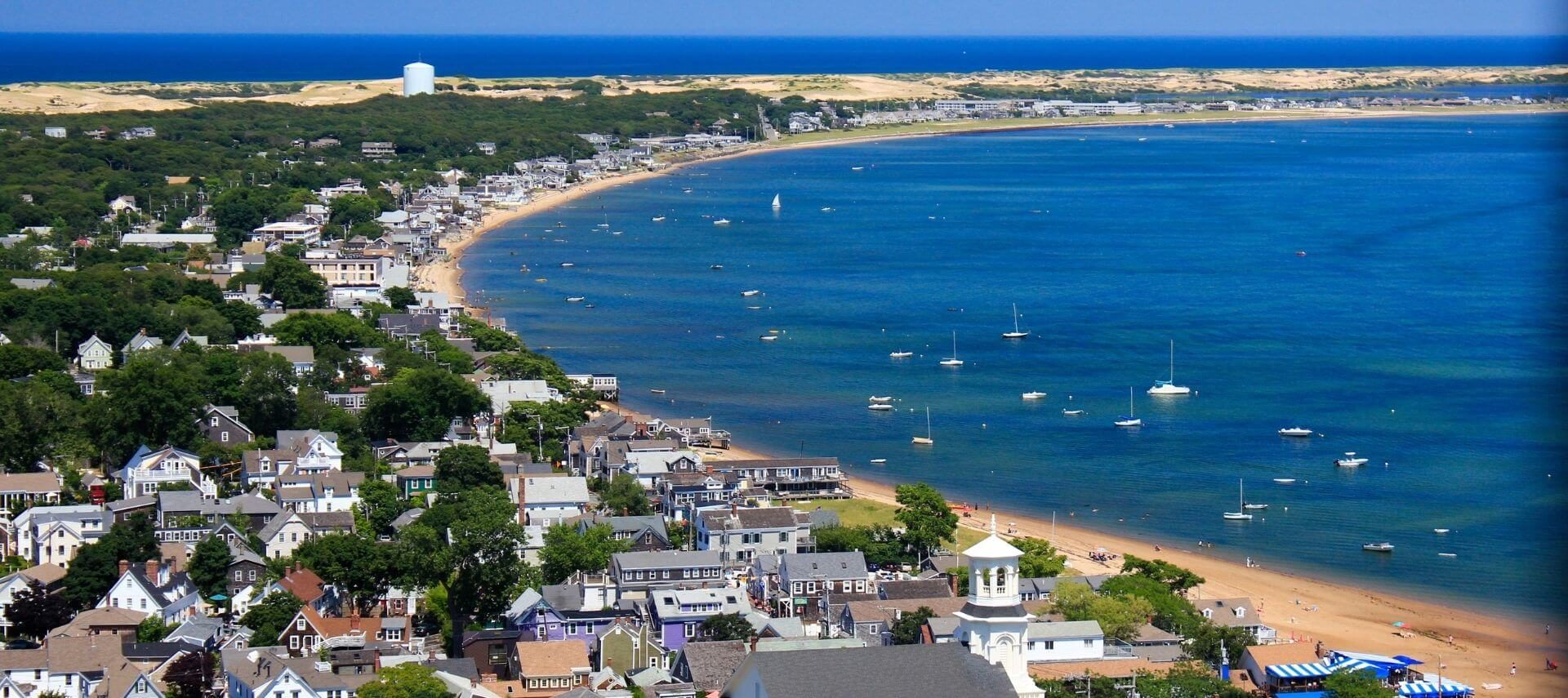 Aerial view of Provincetown, MA with boats on water with houses along beach