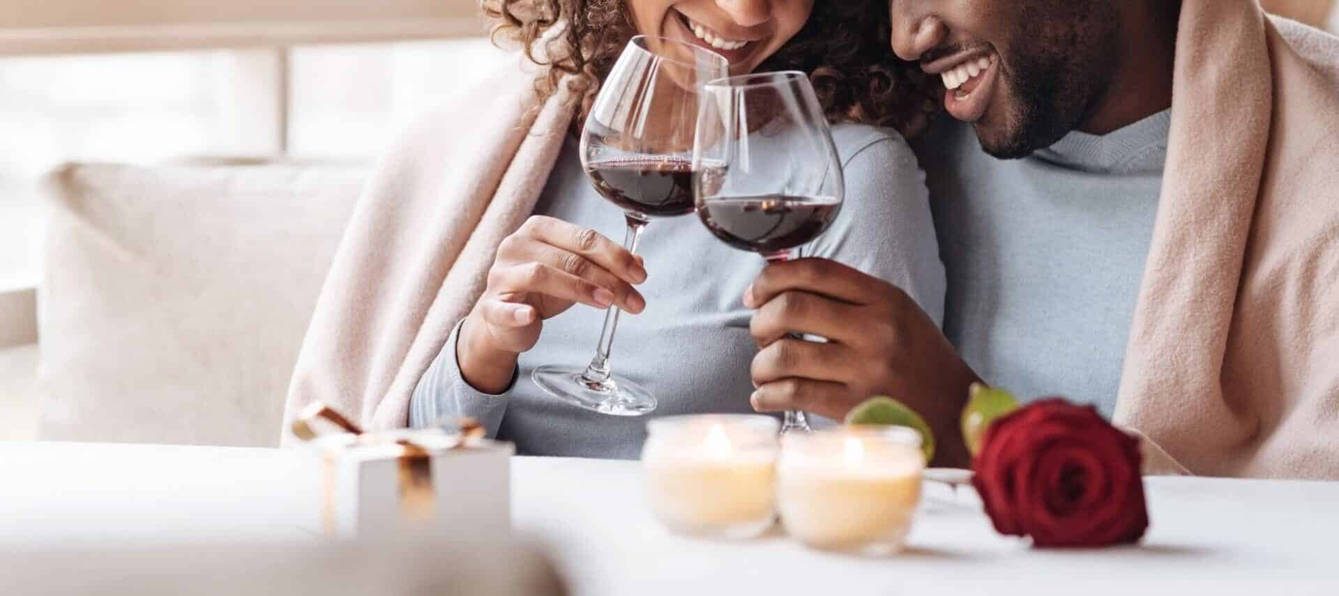 Couple clinking wine glasses while snuggling on a sofa