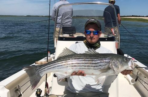 Fisherman shows large bass caught on fishing trip